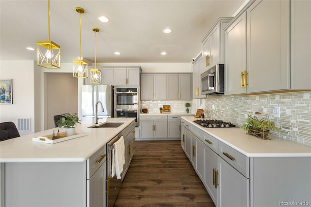 kitchen with tasteful backsplash, an island with sink, dark wood-type flooring, appliances with stainless steel finishes, and sink