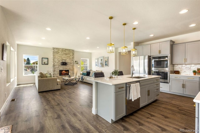 kitchen featuring appliances with stainless steel finishes, gray cabinets, a fireplace, and dark hardwood / wood-style flooring