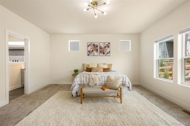 carpeted bedroom with a notable chandelier and ensuite bathroom