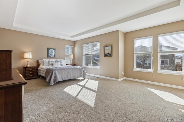 bedroom featuring light colored carpet, baseboards, and a tray ceiling