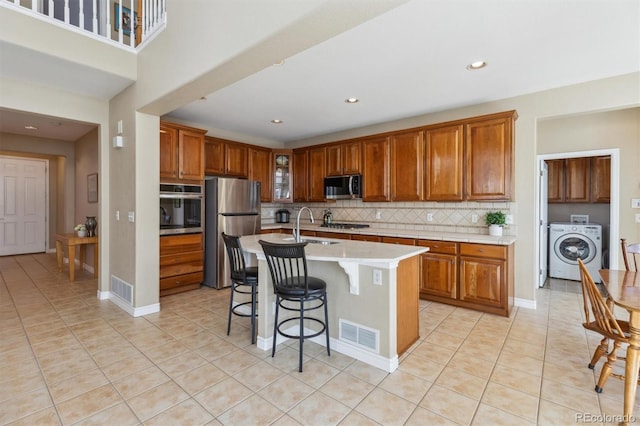 kitchen featuring visible vents, light countertops, washer / dryer, appliances with stainless steel finishes, and a sink