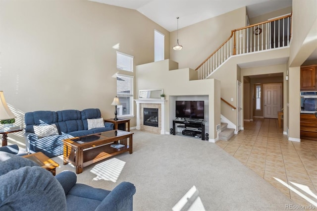 living room featuring a tiled fireplace, stairway, light tile patterned flooring, baseboards, and light colored carpet