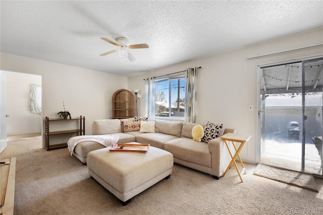 carpeted living room with a textured ceiling and ceiling fan