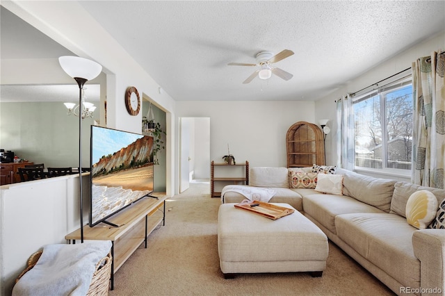 carpeted living area featuring ceiling fan with notable chandelier and a textured ceiling