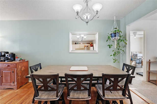 dining room featuring a notable chandelier, a textured ceiling, and light wood-type flooring