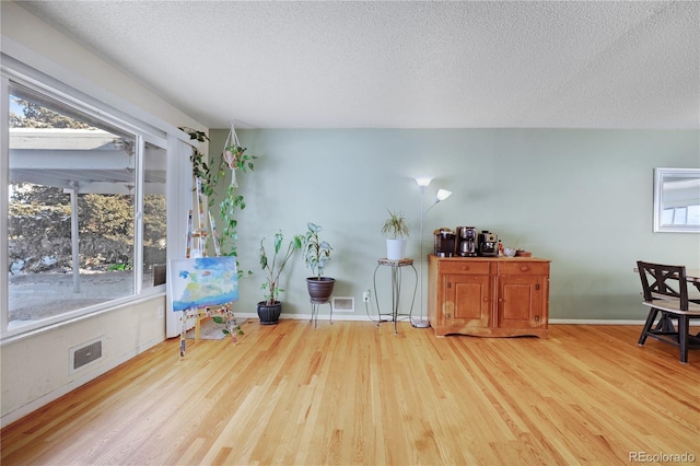 sitting room with visible vents, a healthy amount of sunlight, and wood finished floors