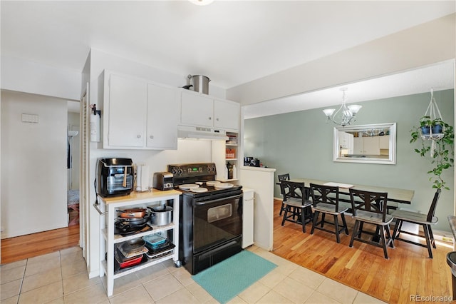 kitchen with light tile patterned floors, an inviting chandelier, electric range, white cabinets, and under cabinet range hood