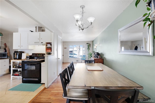 dining area with a chandelier, light wood finished floors, and a textured ceiling