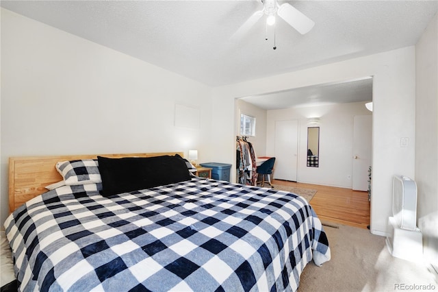 bedroom with a textured ceiling, light colored carpet, and ceiling fan