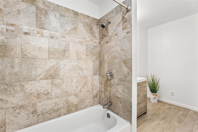 bathroom featuring baseboards, shower / bathing tub combination, wood finished floors, a textured ceiling, and vanity