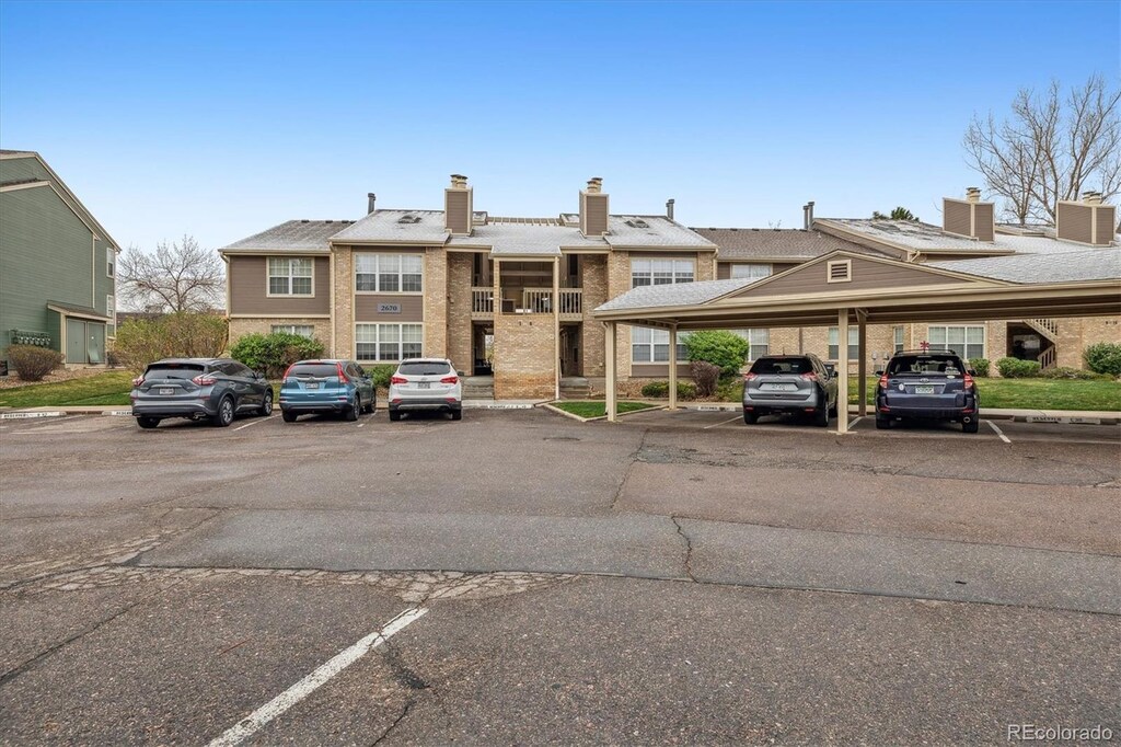 2670 E Otero Pl Unit 11, Centennial, CO 80122 - view of front of property featuring brick siding, covered and uncovered parking, and a chimney