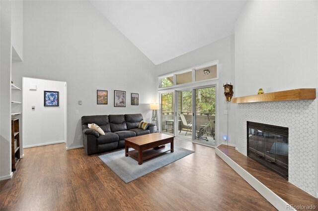 23551 Genesee Village Rd Unit H, Golden, CO 80401 - living room featuring high vaulted ceiling, a tiled fireplace, wood finished floors, and baseboards