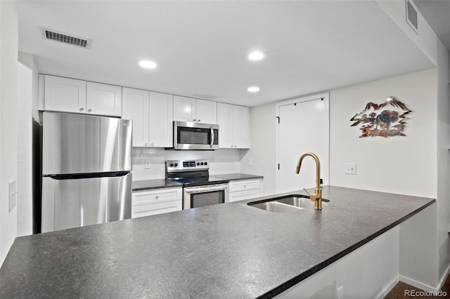 23551 Genesee Village Rd Unit H, Golden, CO 80401 - kitchen with appliances with stainless steel finishes, a sink, dark countertops, a peninsula, and white cabinets