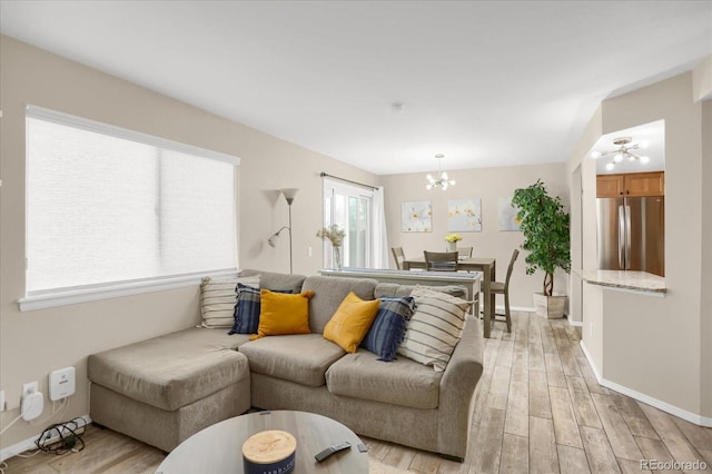 living room featuring a chandelier, light wood finished floors, and baseboards