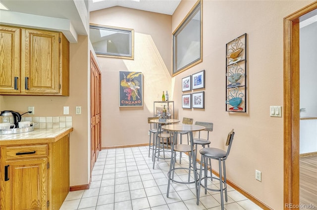 kitchen featuring tile counters, light tile patterned floors, and lofted ceiling