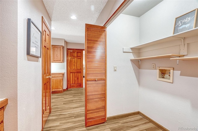 laundry room with light hardwood / wood-style flooring, hookup for a washing machine, and a textured ceiling