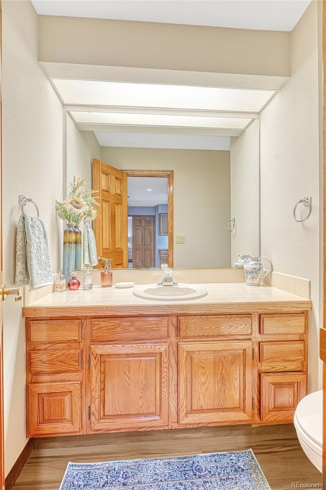 bathroom with hardwood / wood-style floors, toilet, and vanity