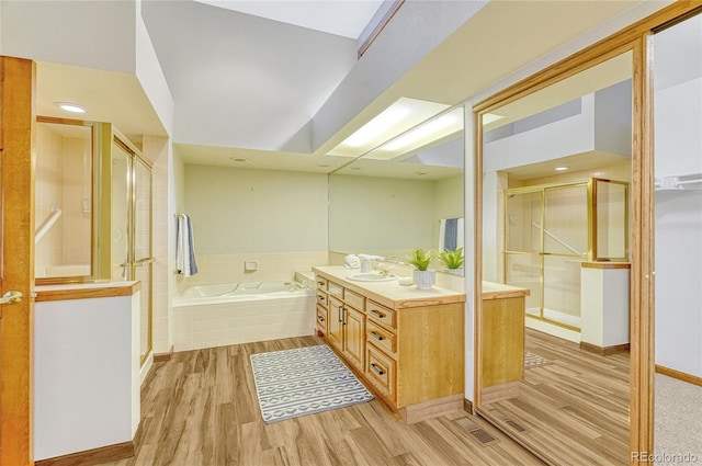 bathroom with shower with separate bathtub, hardwood / wood-style flooring, and vanity