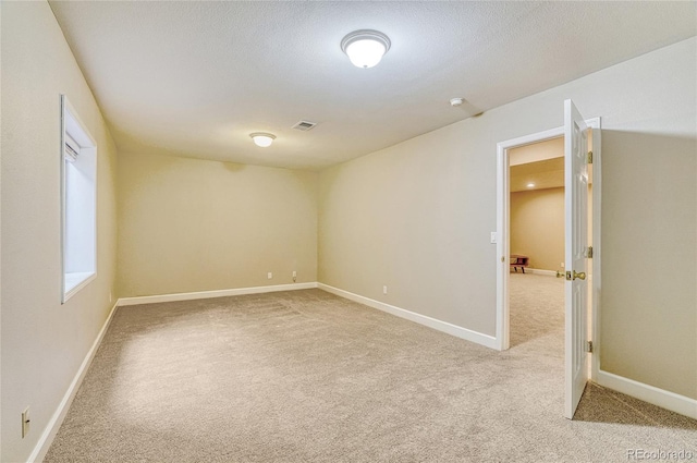 empty room featuring light carpet and a textured ceiling