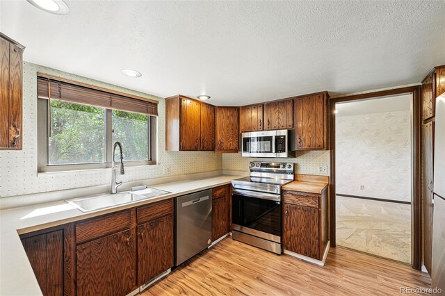 1354 S Macon St, Aurora, CO 80012 - kitchen featuring stainless steel appliances, a sink, light wood-style flooring, light countertops, and a textured ceiling