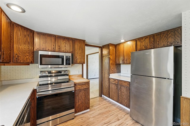 1354 S Macon St, Aurora, CO 80012 - kitchen with appliances with stainless steel finishes, light countertops, light wood-type flooring, decorative backsplash, and brown cabinetry