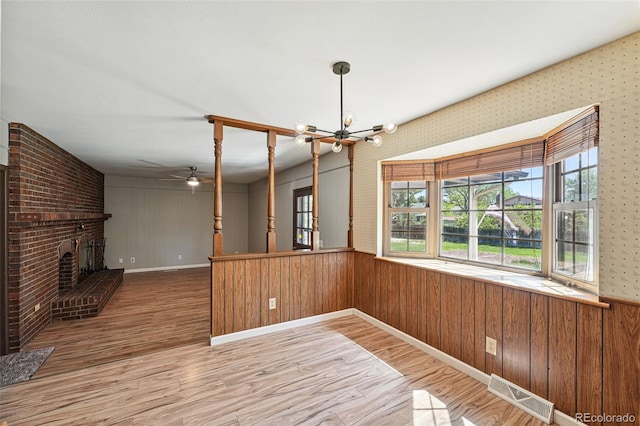1354 S Macon St, Aurora, CO 80012 - unfurnished dining area with wood finished floors, a chandelier, ceiling fan, a brick fireplace, and wood walls