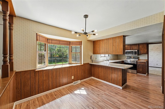 1354 S Macon St, Aurora, CO 80012 - kitchen featuring stainless steel appliances, light wood finished floors, a peninsula, a chandelier, and a sink