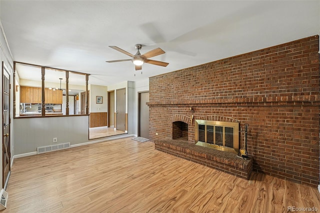 1354 S Macon St, Aurora, CO 80012 - unfurnished living room with wood finished floors, ceiling fan, brick wall, and a fireplace