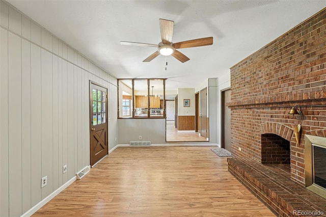 1354 S Macon St, Aurora, CO 80012 - unfurnished living room with light wood-style flooring, a brick fireplace, ceiling fan, and baseboards