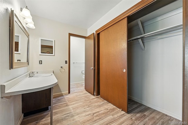 1354 S Macon St, Aurora, CO 80012 - bathroom with wood finished floors, toilet, vanity, and baseboards