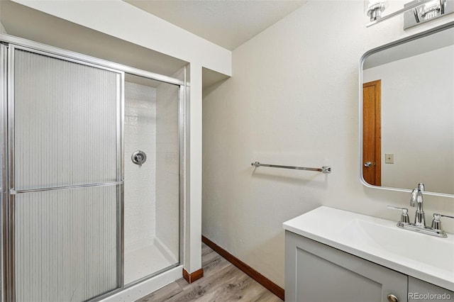 1354 S Macon St, Aurora, CO 80012 - bathroom featuring wood finished floors, a shower stall, vanity, and baseboards