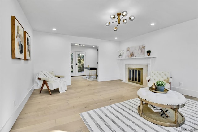 living room featuring a fireplace, light wood-style floors, recessed lighting, french doors, and baseboards