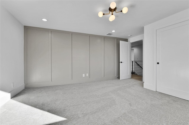 unfurnished bedroom with carpet, a chandelier, recessed lighting, and a decorative wall