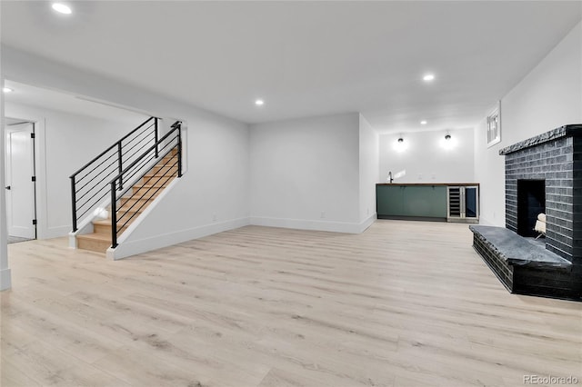 unfurnished living room featuring light wood-style floors, stairs, recessed lighting, a fireplace, and baseboards