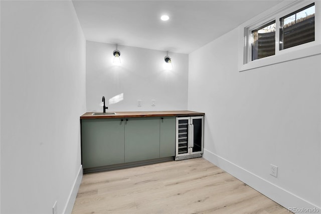 indoor wet bar with wine cooler, baseboards, light wood-type flooring, and recessed lighting