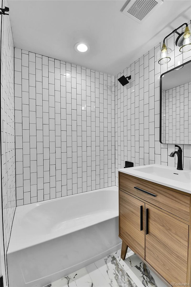 full bath featuring marble finish flooring, vanity, tile walls, and shower / bath combination