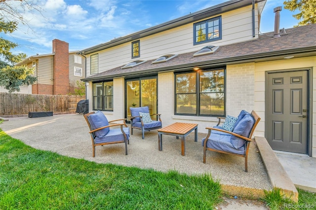 back of property with a patio area, brick siding, fence, and roof with shingles