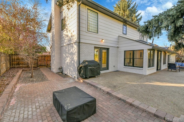 back of property with brick siding, a fenced backyard, and a patio area