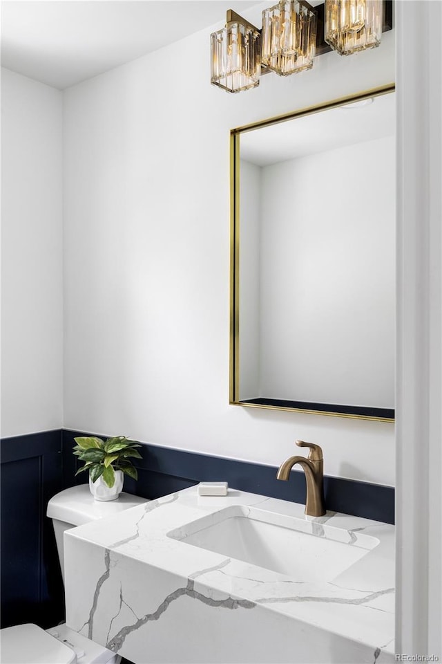 3930 S Hillcrest Dr, Denver, CO 80237 - half bath featuring a chandelier, vanity, toilet, and a wainscoted wall