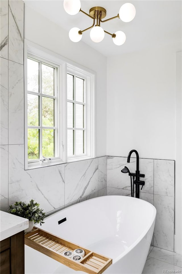 3930 S Hillcrest Dr, Denver, CO 80237 - full bath featuring healthy amount of natural light, a chandelier, tile walls, a freestanding tub, and marble finish floors