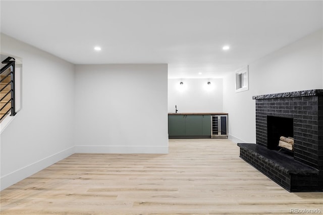 3930 S Hillcrest Dr, Denver, CO 80237 - unfurnished living room with beverage cooler, a brick fireplace, light wood-type flooring, recessed lighting, and baseboards