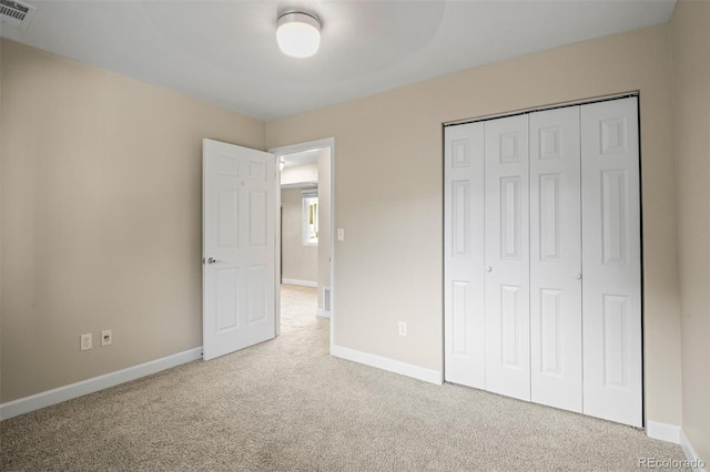 unfurnished bedroom featuring light carpet and a closet