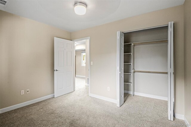 unfurnished bedroom featuring light carpet and a closet