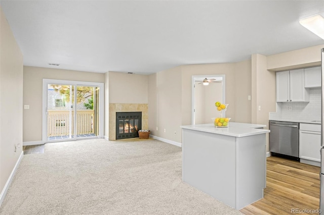 kitchen with stainless steel dishwasher, ceiling fan, tasteful backsplash, a kitchen island, and white cabinetry