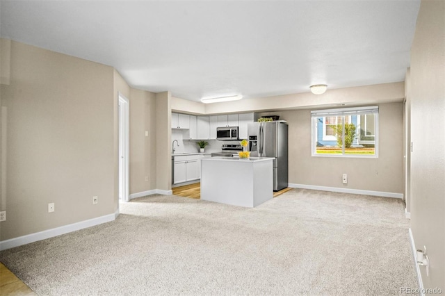 kitchen featuring white cabinetry, a center island, sink, stainless steel appliances, and light colored carpet