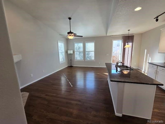 interior space featuring a ceiling fan, dark wood-style flooring, a sink, and baseboards