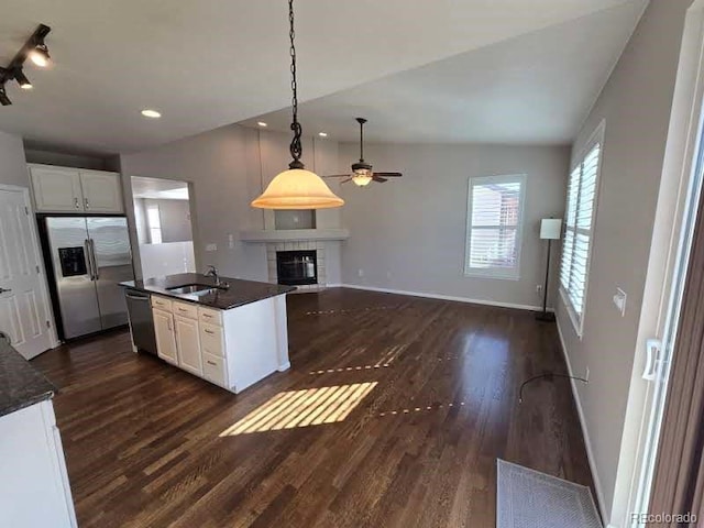 kitchen featuring dark countertops, white cabinetry, a sink, stainless steel fridge, and dishwasher