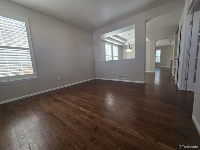 spare room featuring dark wood-style floors, visible vents, and baseboards