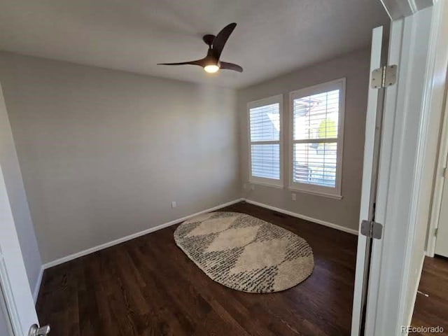 spare room featuring dark wood-style floors, ceiling fan, and baseboards