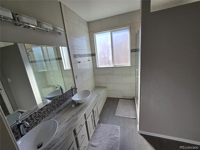 full bath featuring double vanity, a sink, and a shower stall